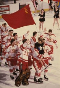 Jogadores da União Soviética comemorando com a bandeira da URSS ao final de uma partida ainda no rinque de gelo.